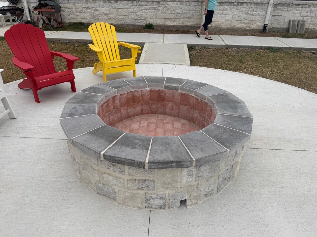 Custom stone fire pit with seating on concrete patio in Houston TX