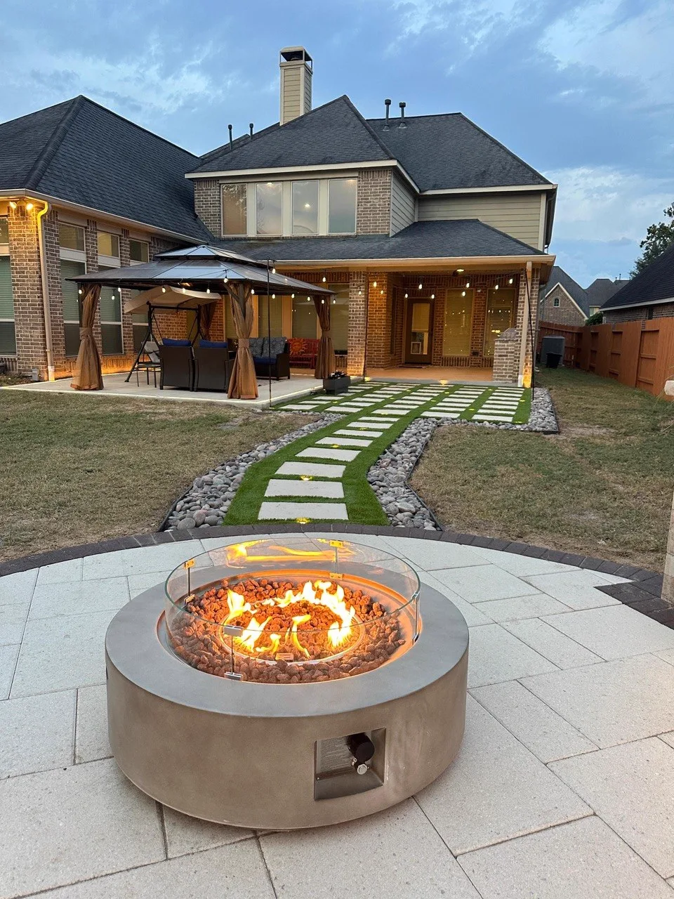 Custom fire pit on paver patio with stone stepping path at dusk in Houston TX