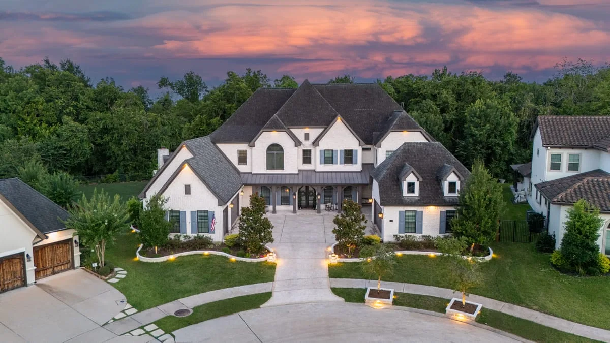 Aerial view of luxury Houston home with circular concrete driveway at sunset