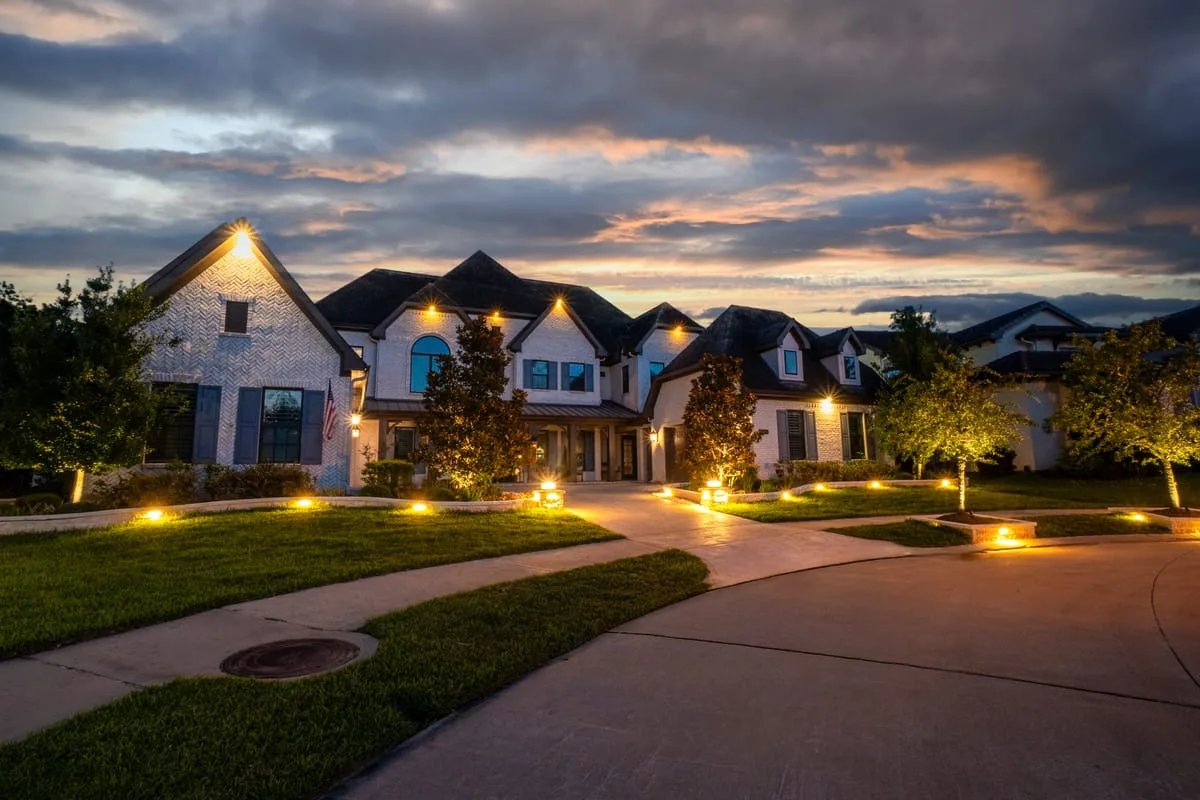 Luxury home driveway with landscape lighting at night in Houston TX