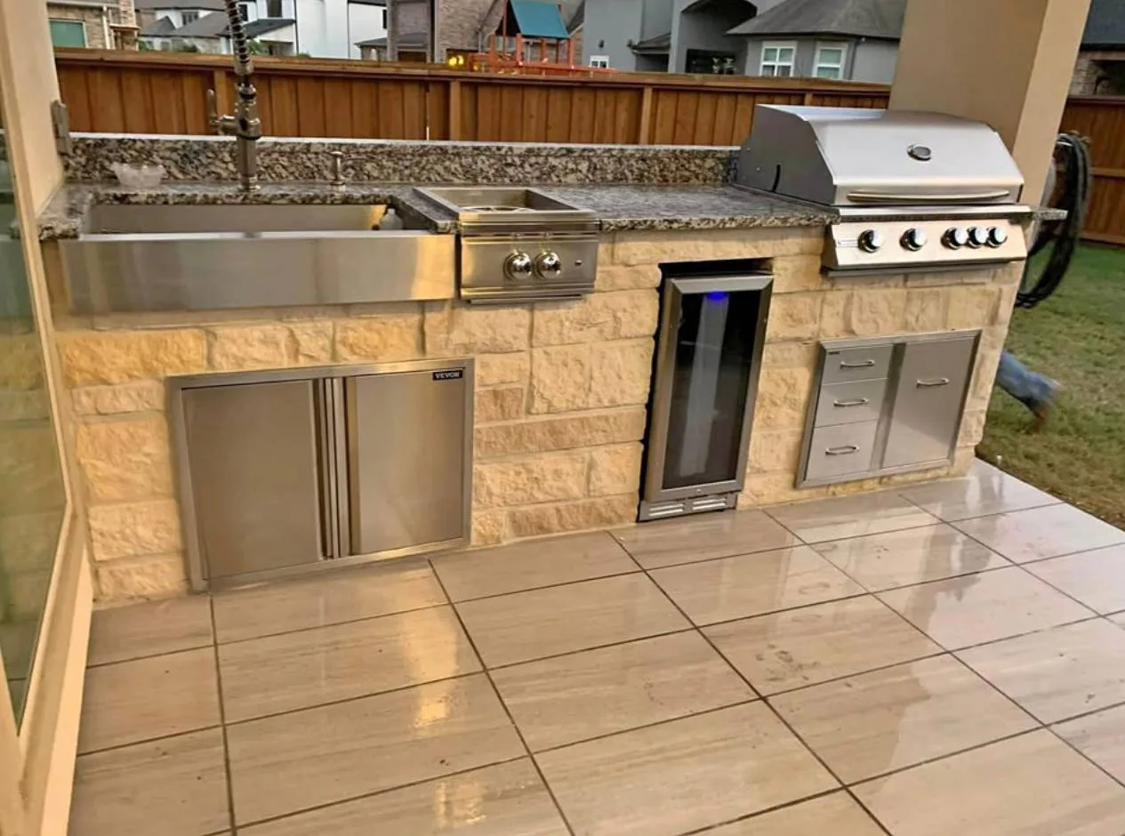 Outdoor kitchen with built-in grill refrigerator and granite counters in Houston TX