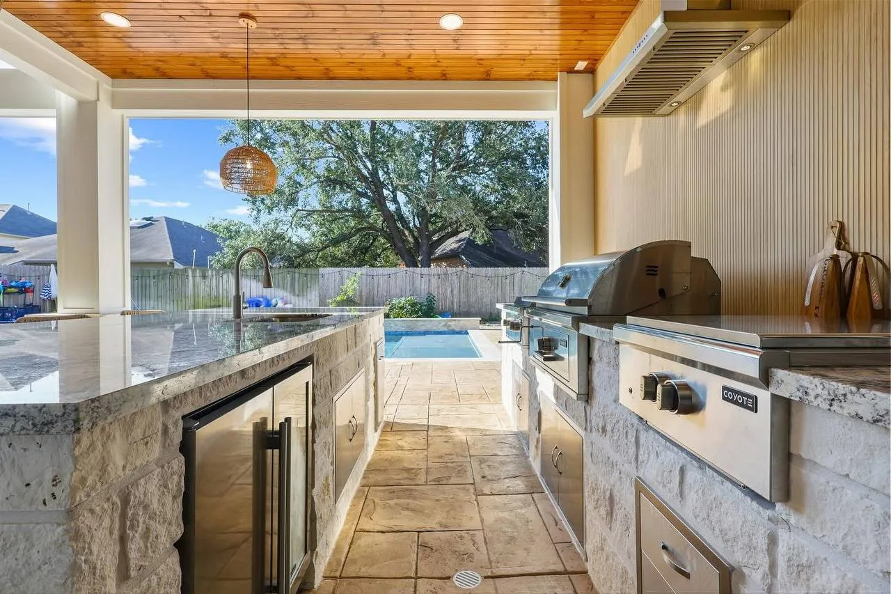 Custom luxury outdoor kitchen with stone island bar and built-in grill in Houston TX