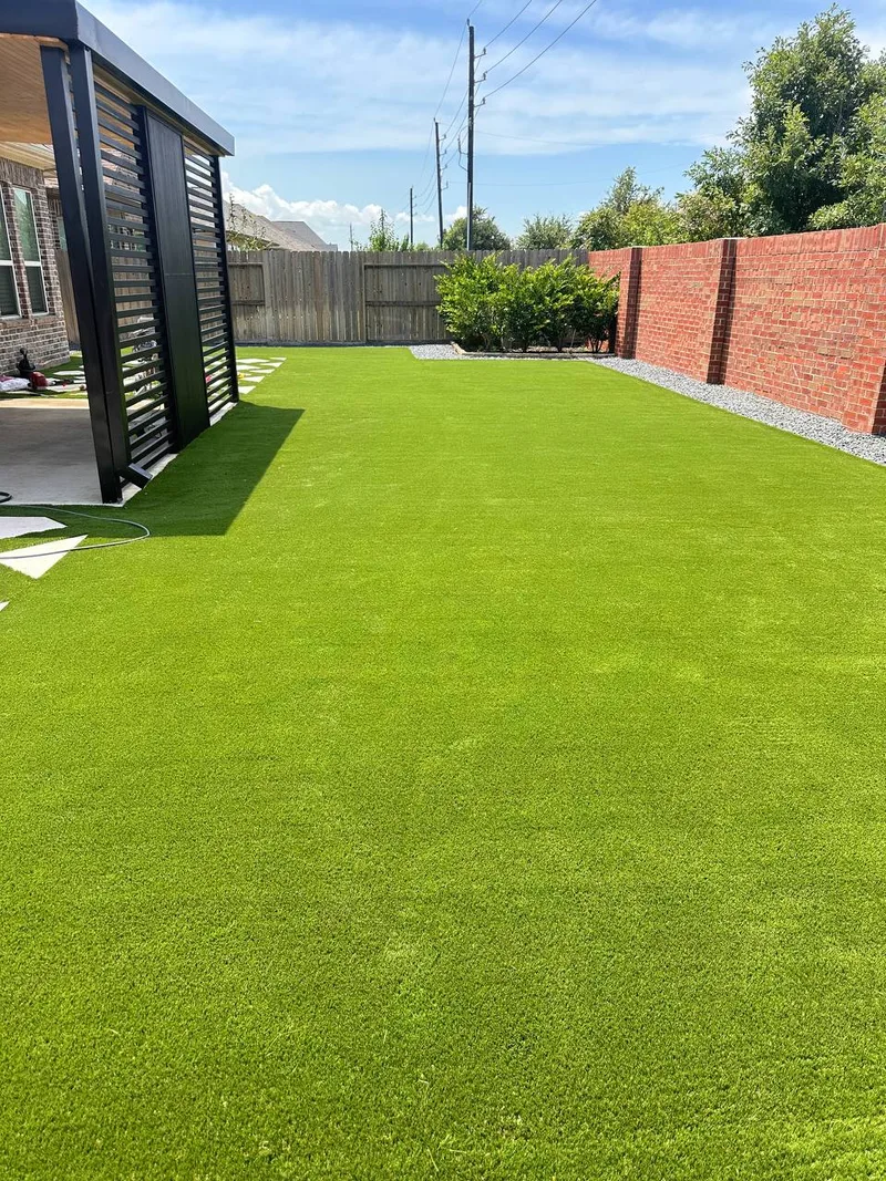 Artificial turf backyard with modern black louvered pergola installed in Cypress TX