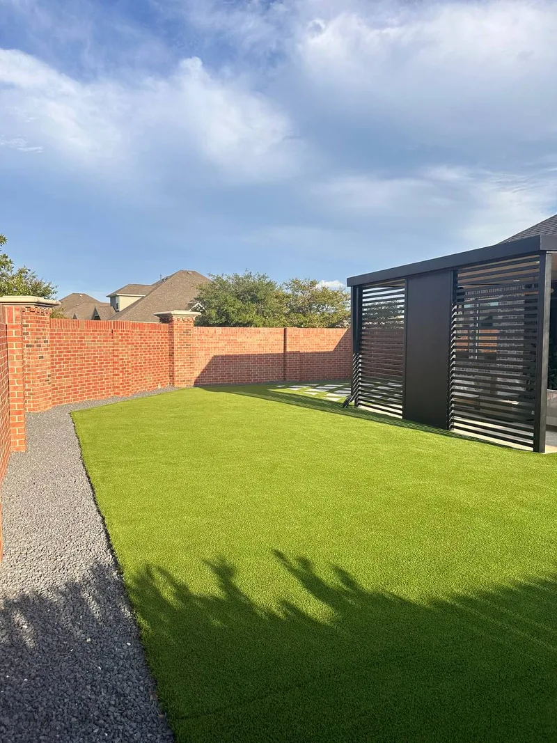 Artificial turf with gravel border and black aluminum louvered pergola in Cypress TX