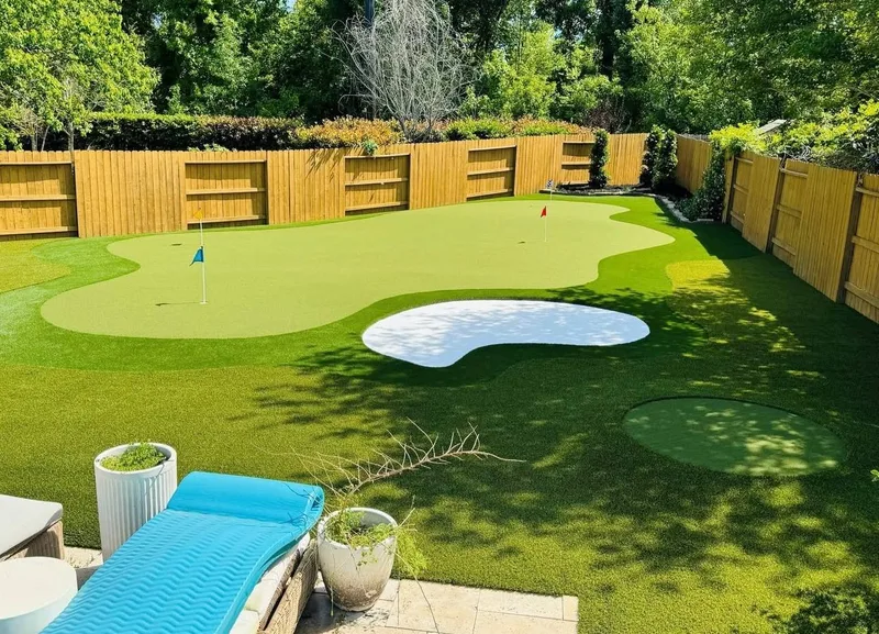 Backyard putting green with multiple holes, sand bunker, and lounge area in Cypress TX