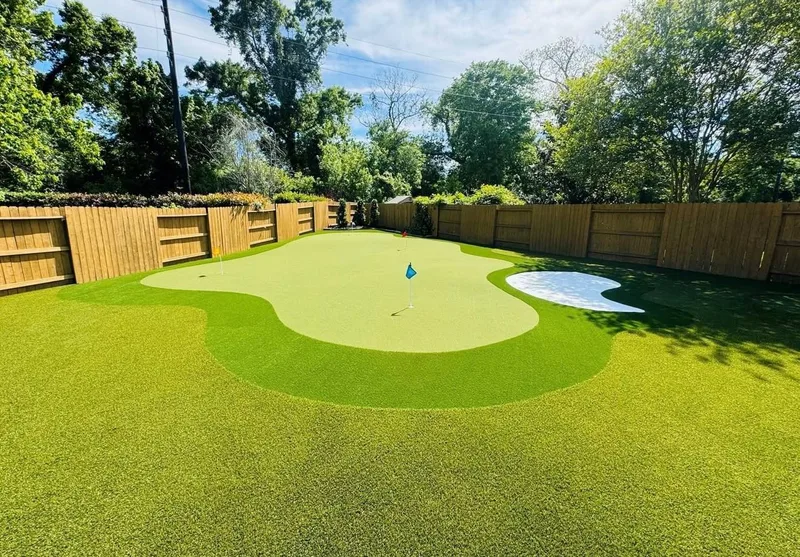 Custom putting green with sand bunker and cedar wood fence in Cypress TX