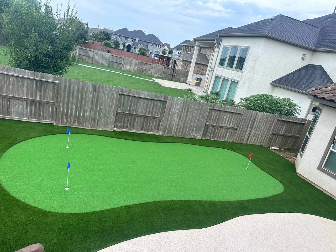 Custom artificial turf putting green with 3 holes and flags in Houston TX backyard