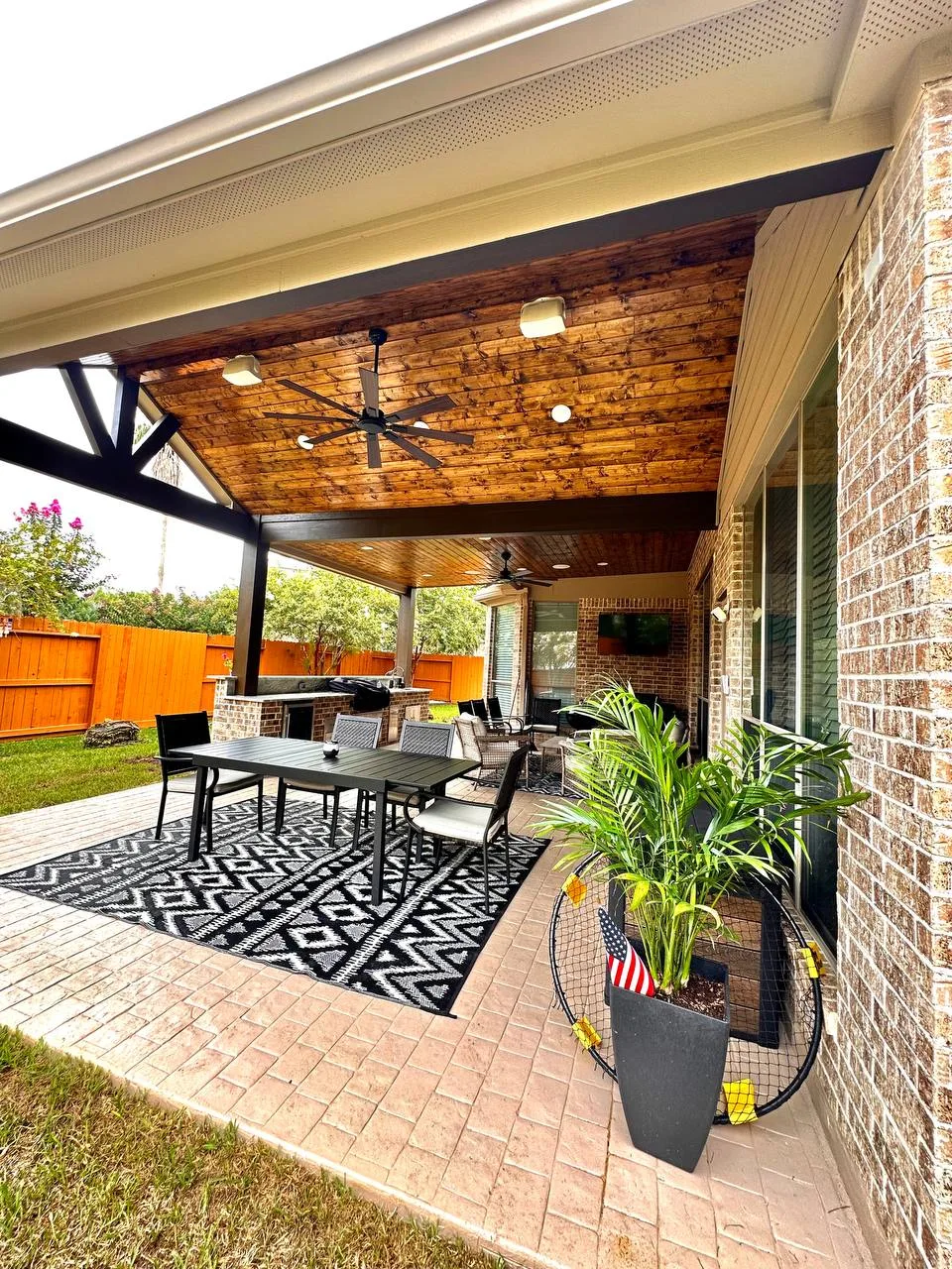 Covered patio with tongue-and-groove wood ceiling, steel frame, ceiling fans and outdoor dining in Houston TX