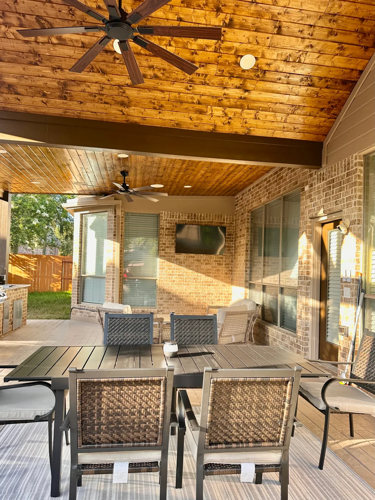 Covered patio with cedar wood ceiling fans TV and outdoor dining in Houston TX