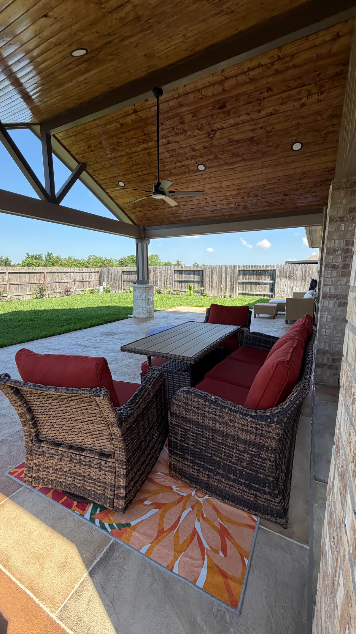 Gable patio cover with ceiling fan wicker furniture and travertine in Houston TX