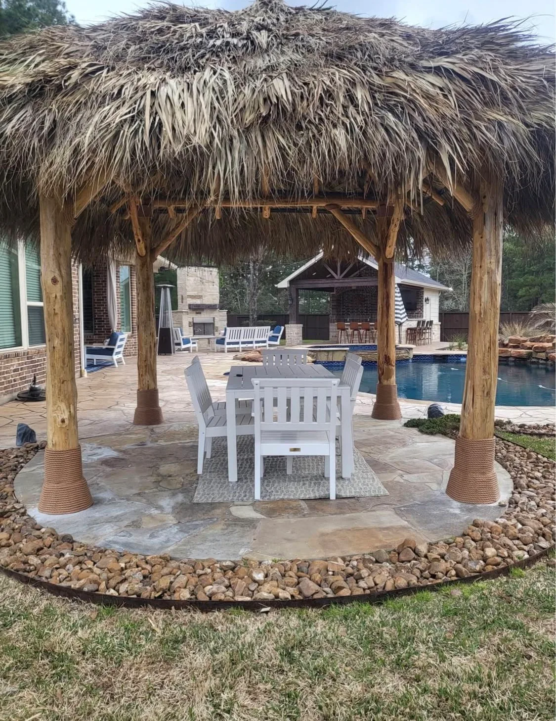 Tiki palapa pergola with outdoor dining table and pool view in Houston TX