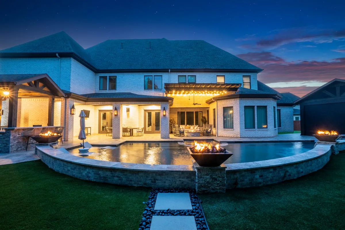 Luxury Houston backyard at night with pool fire bowls pergola and outdoor seating