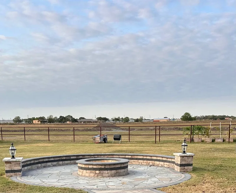 Stone fire pit with flagstone circular patio and pillar lanterns in Rosenberg TX